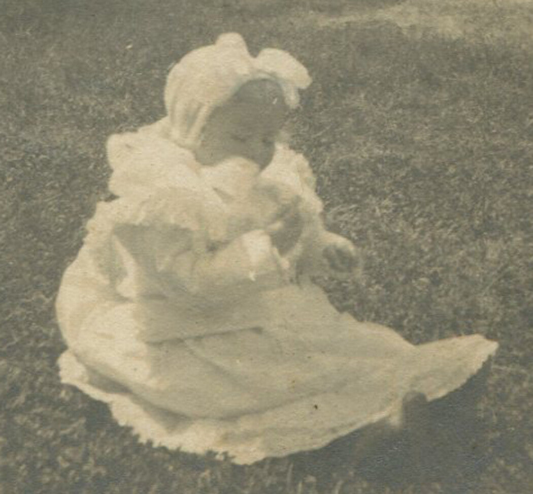 BABY SEATED ON LAWN. ROUND SILVER PRINT, MOUNTED ON CARD. 4.25 X 4.25 IN.