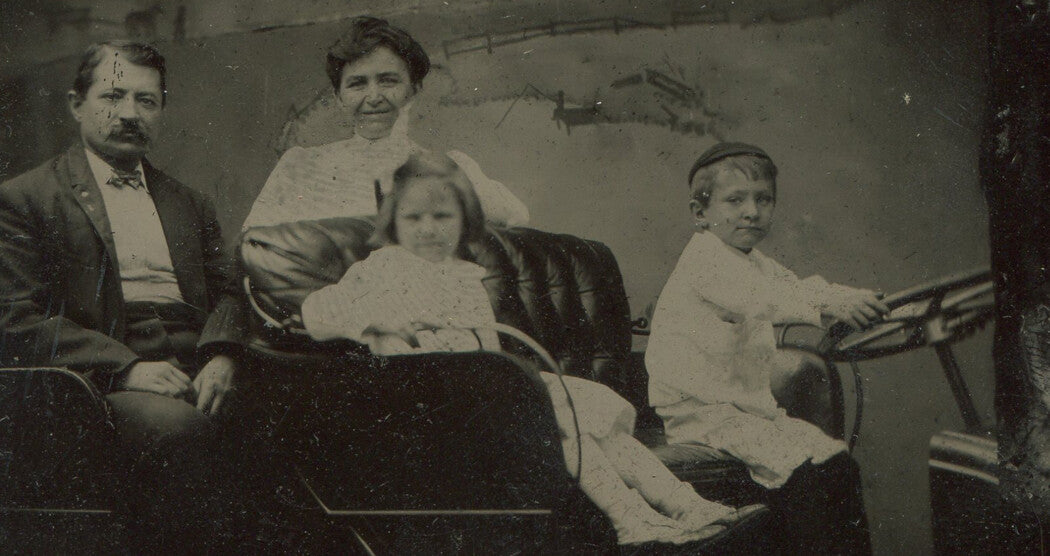 YOUNG CHILDREN, PARENTS, POSED IN VERY EARLY MODEL CAR. STUDIO PROP. TINTYPE.