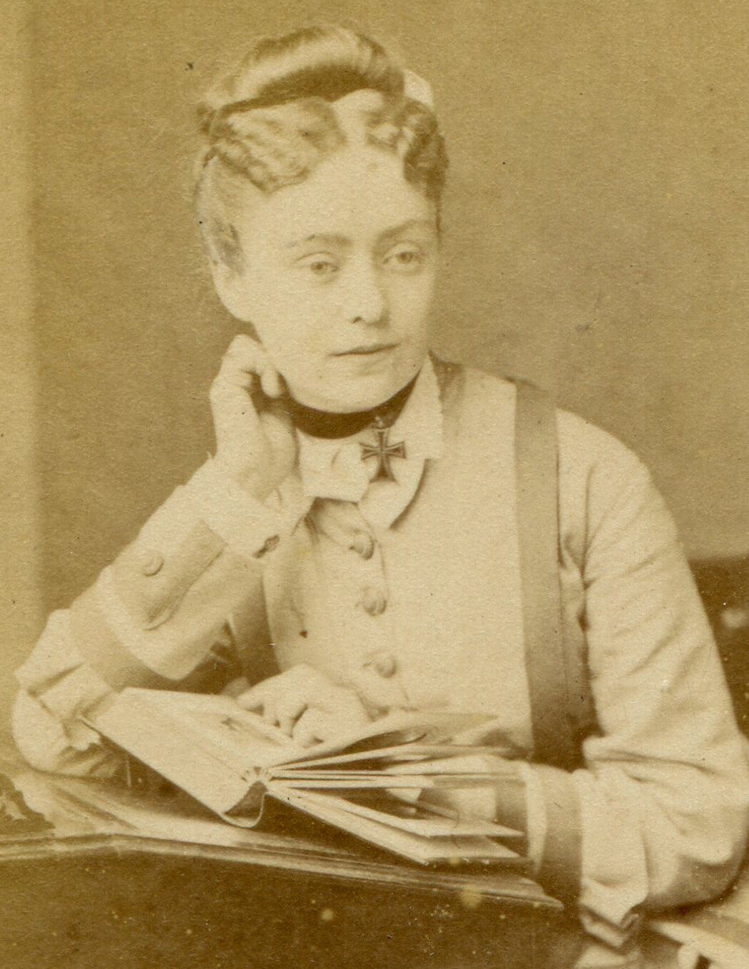 WOMAN WEARING IRON CROSS, POSED READING AT TABLE. CDV. ENGLAND.