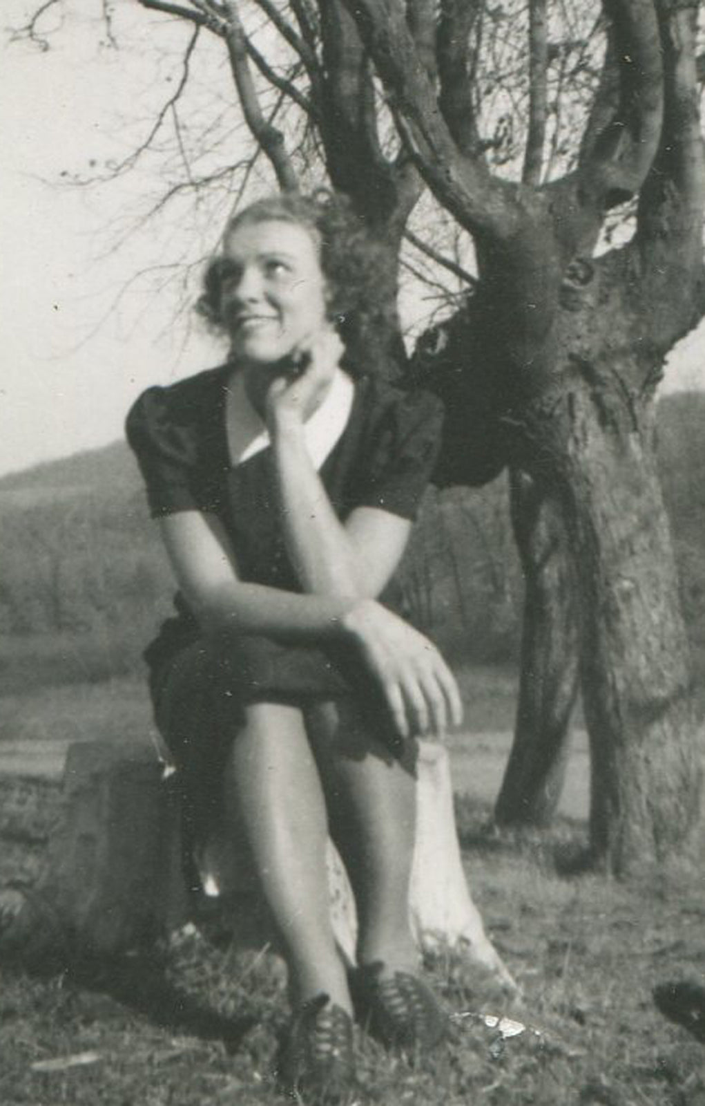 WOMAN SEATED AT FOOT OF BARE TREE. SILVER PRINT 5 X 3.25 INCHES. 1950s.