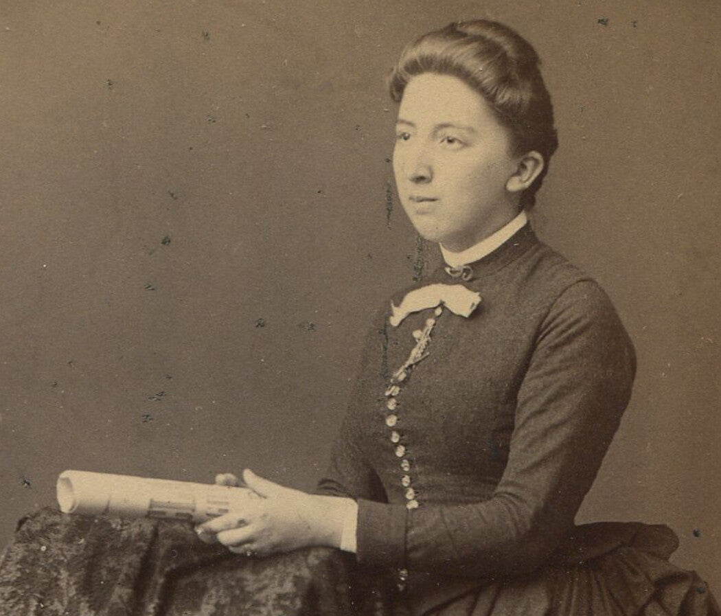 WOMAN POSED WITH DIPLOMA, LARGE DRESS BUSTLE. CABINET CARD.