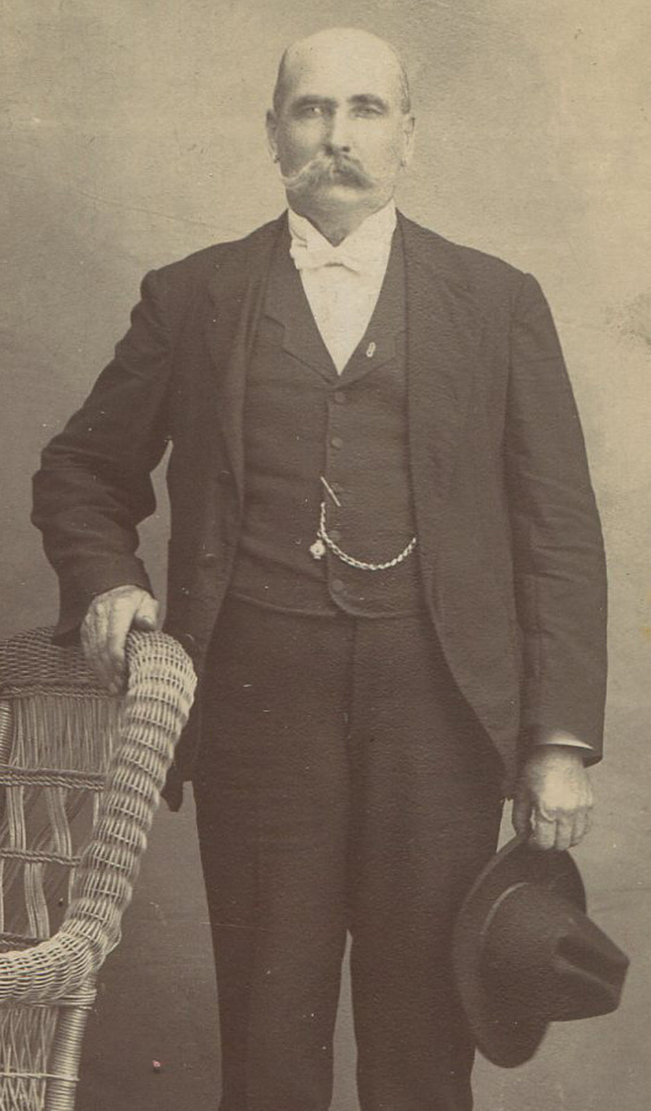 MAN W/BIG MUSTACHE, STIFFLY POSED HOLDING HAT. CABINET CARD.