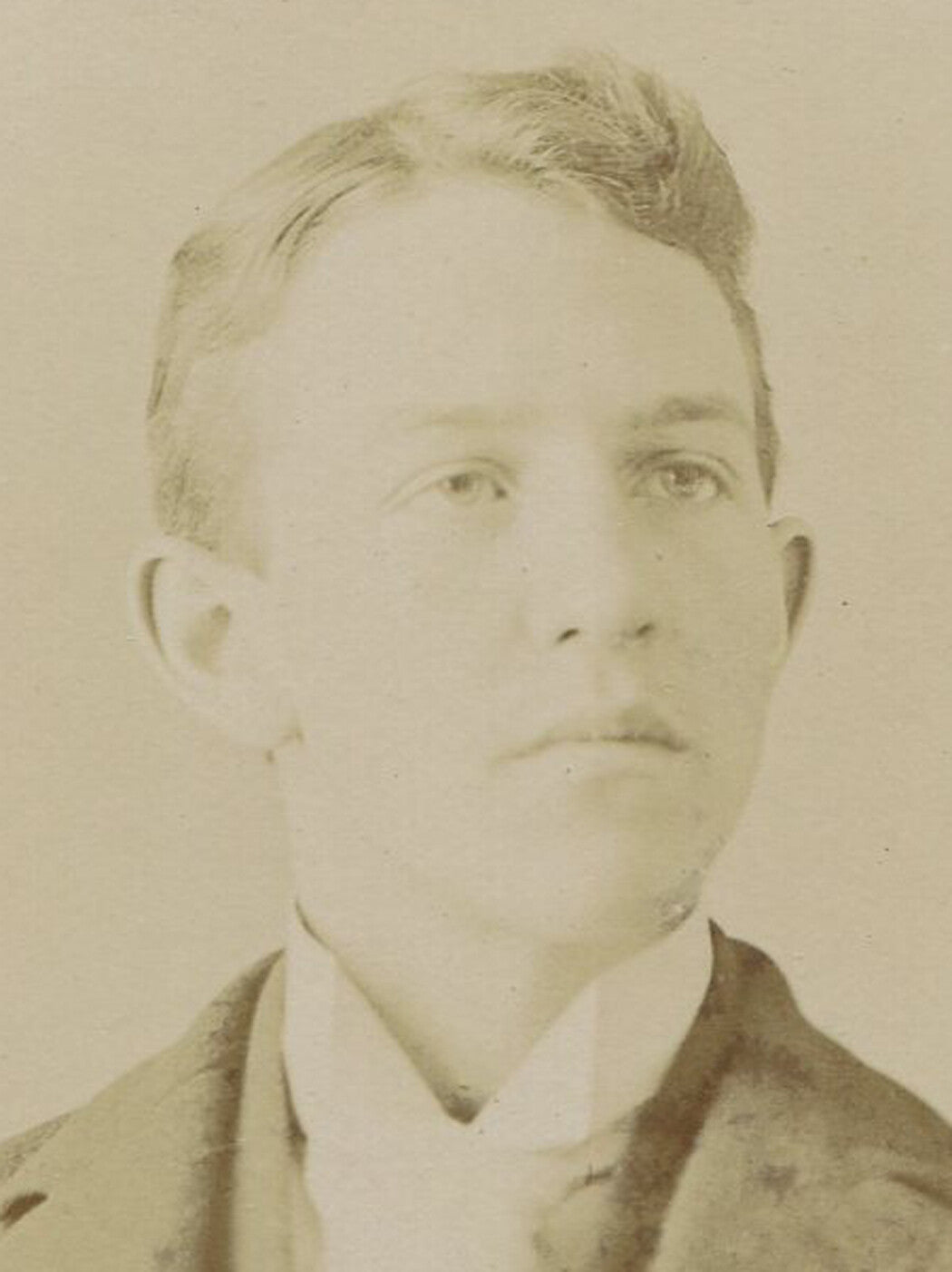 YOUNG MAN WITH ANGULAR FEATURES. SILVER PRINT ON EMBOSSED BOARD. CIRCA 1900.