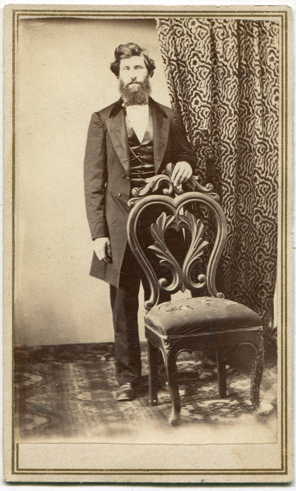 MAN WITH WILD HAIR POSED IN FRONT OF RICHLY PATTERNED CURTAINS. CDV.