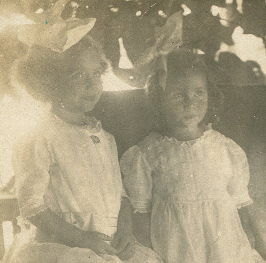 TWO YOUNG GIRLS ON ROCKING CHAIR, LEAFY SETTING. B W 5 X 4 INCHES.