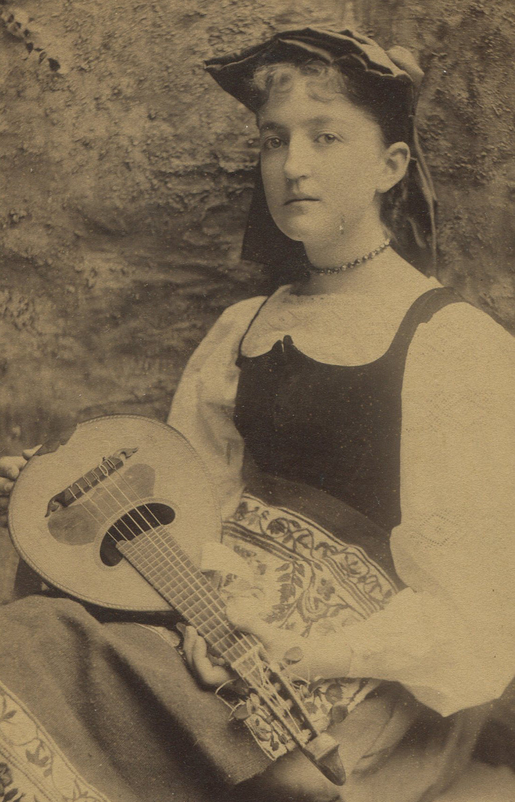 YOUNG WOMAN IN TRADITIONAL WEAR, HOLDING FOLK INSTRUMENT. CABINET CARD.