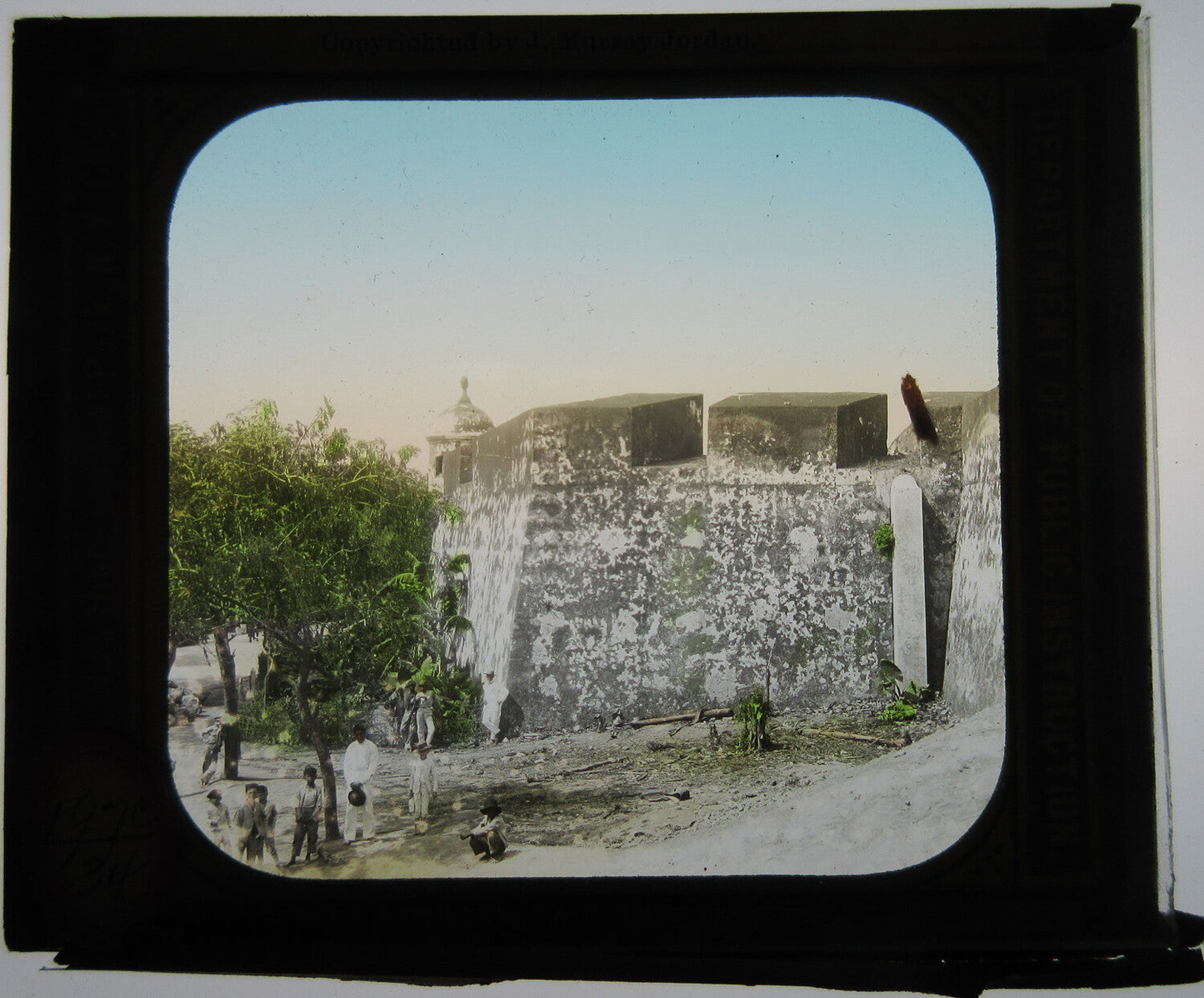 Vintage magic lantern slide: People outside fortress walls, tropical setting, tinted photo, original