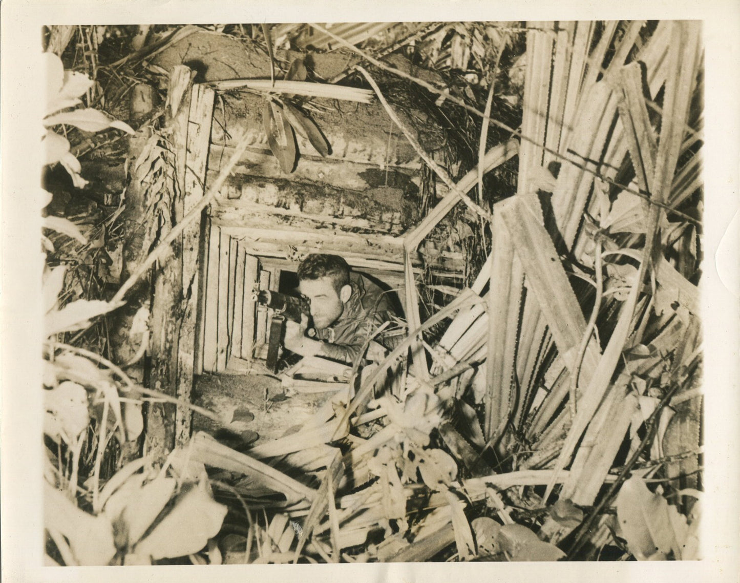 U.S.SOLDIER IN CAPTURED JAPANESE MACHINE GUN NEST. NEW GUINEA WWII(8X10 REPRINT)