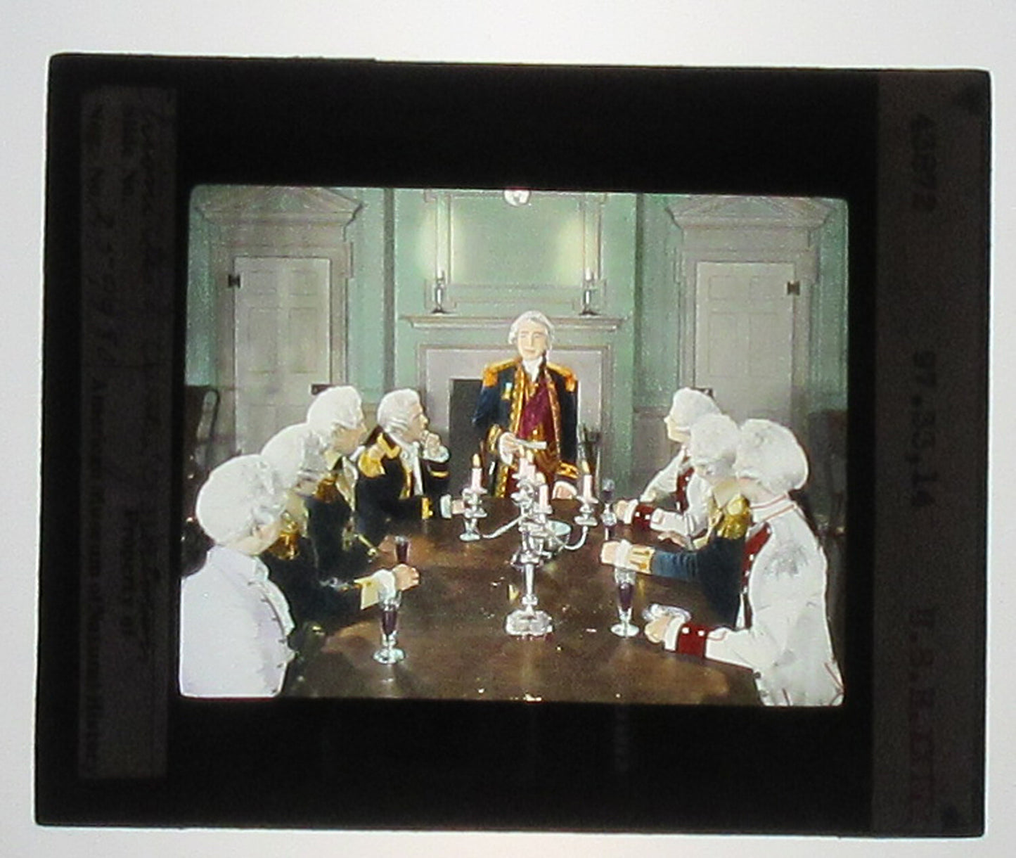 ACTORS PORTRAY REVOLUTIONARY WAR SETTING. HAND COLORED PHOTO ON GLASS.