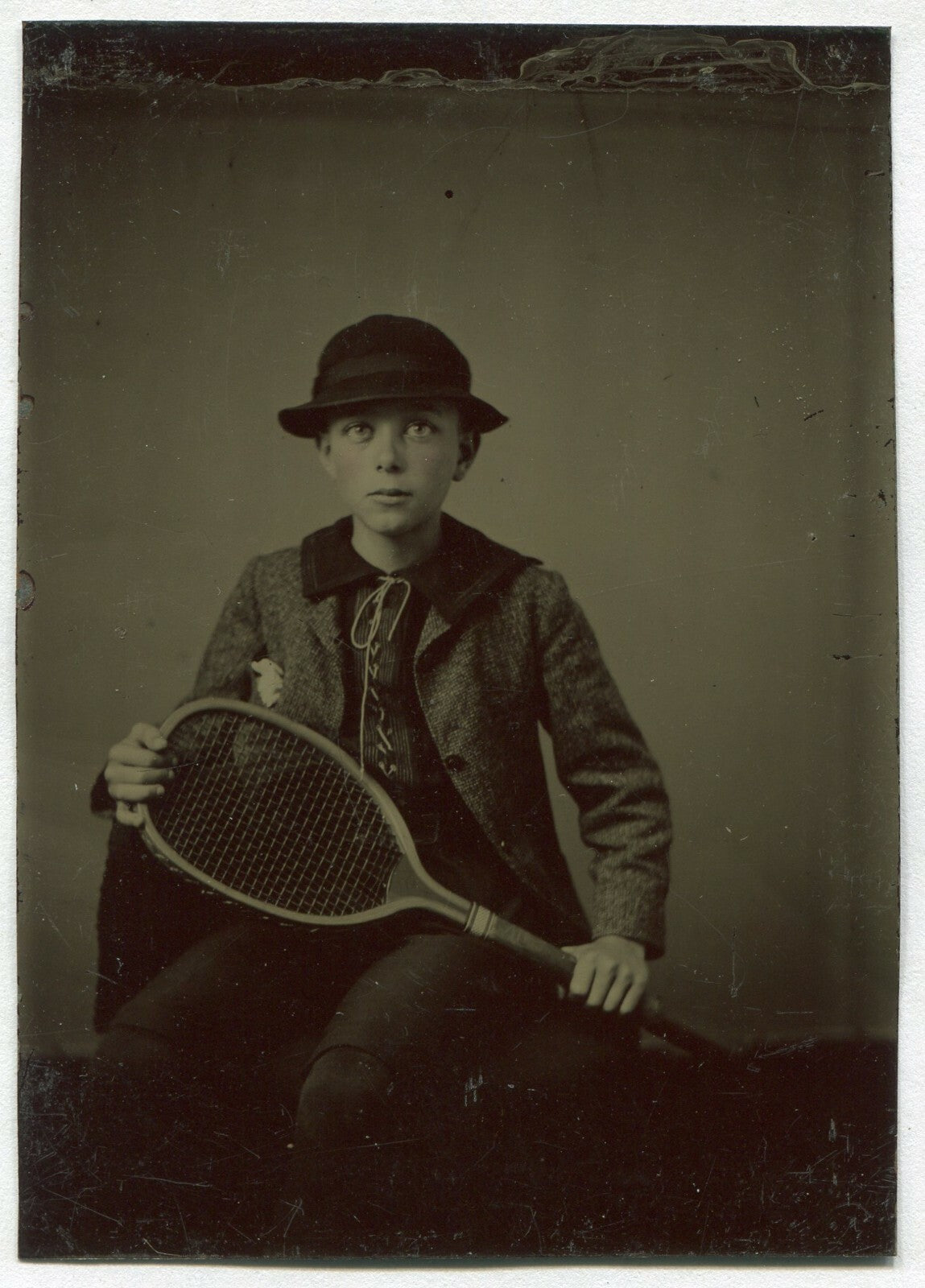 YOUNG BOY IN HAT, POSED W/TENNIS RACKET. TINTED TINTYPE.