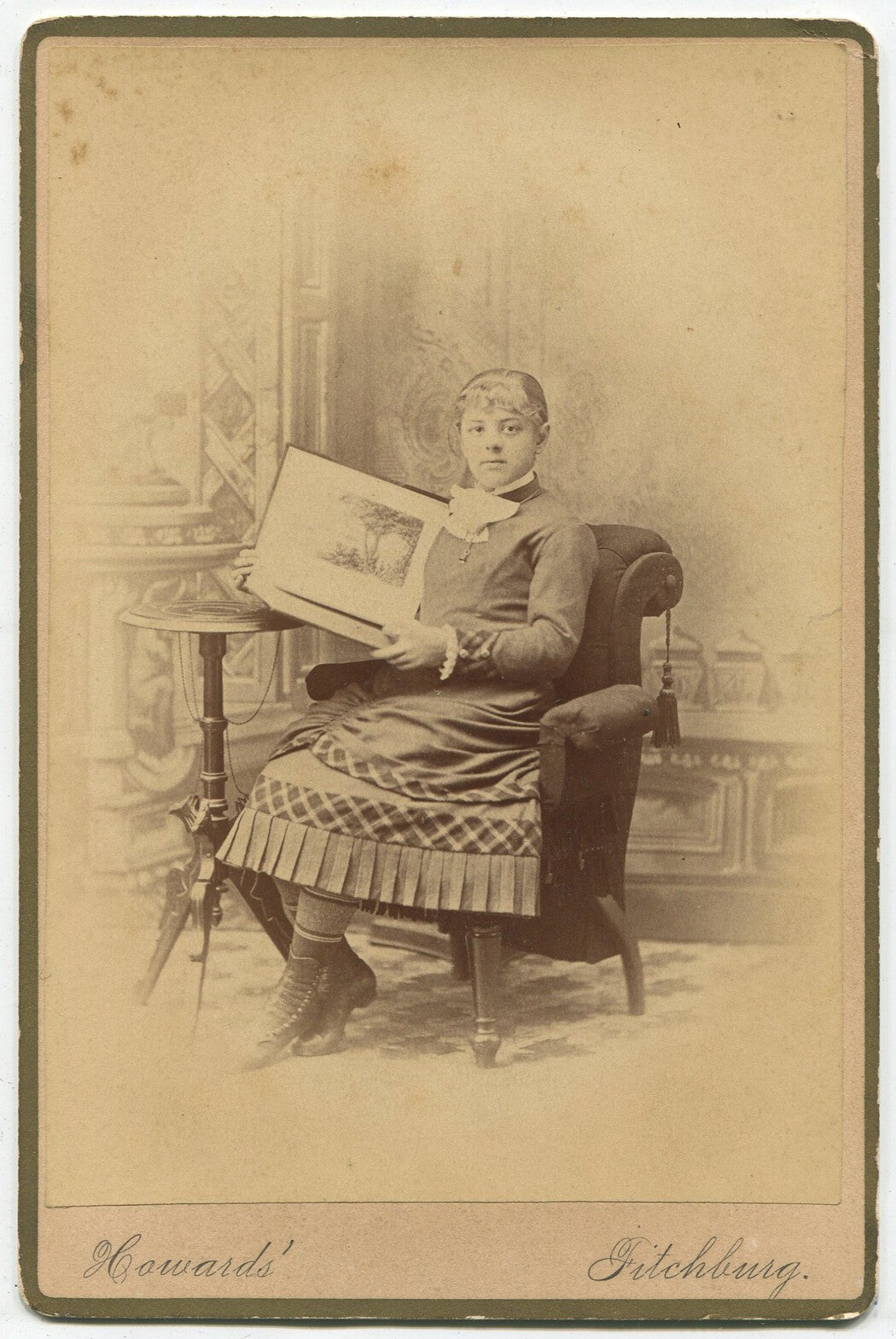 Vintage cabinet card portrait: young girl seated, holding a picture book -