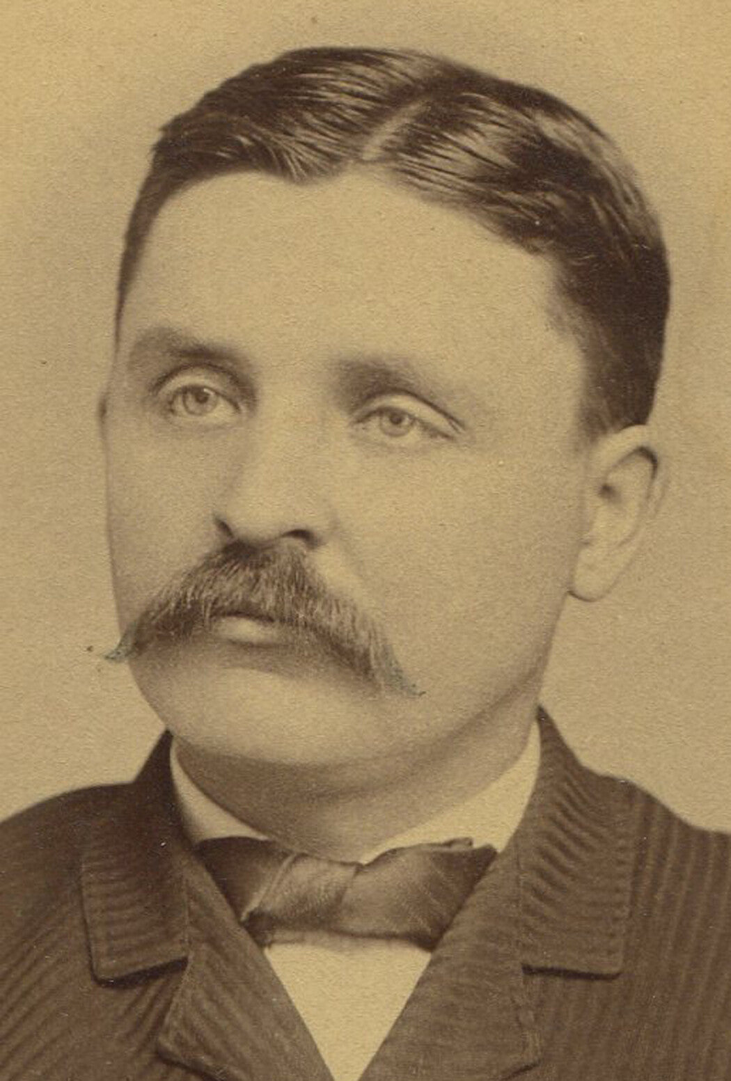 BORED, ROUND FACED MAN WITH THICK MUSTACHE. CABINET CARD, NICKERSON, KANSAS.