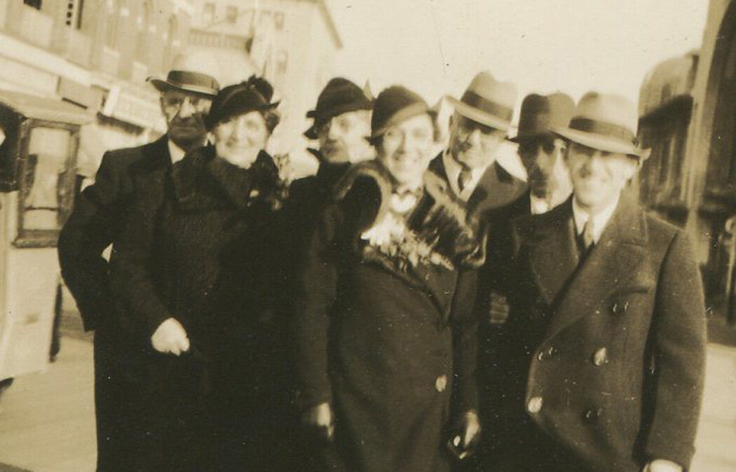 HAPPY COAT AND HAT WEARING GROUP OF TRAVELERS. STREET SCENE, 1940s.