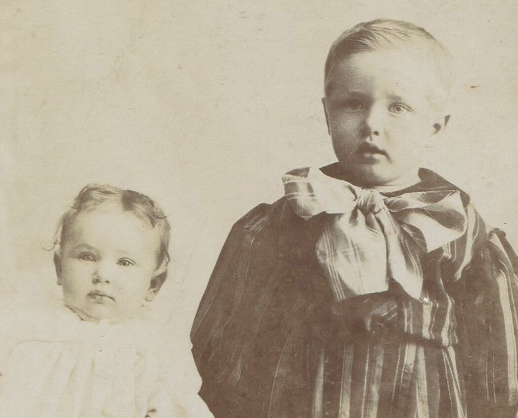 Vintage cabinet card photo: two very young siblings in unsteady pose, studio