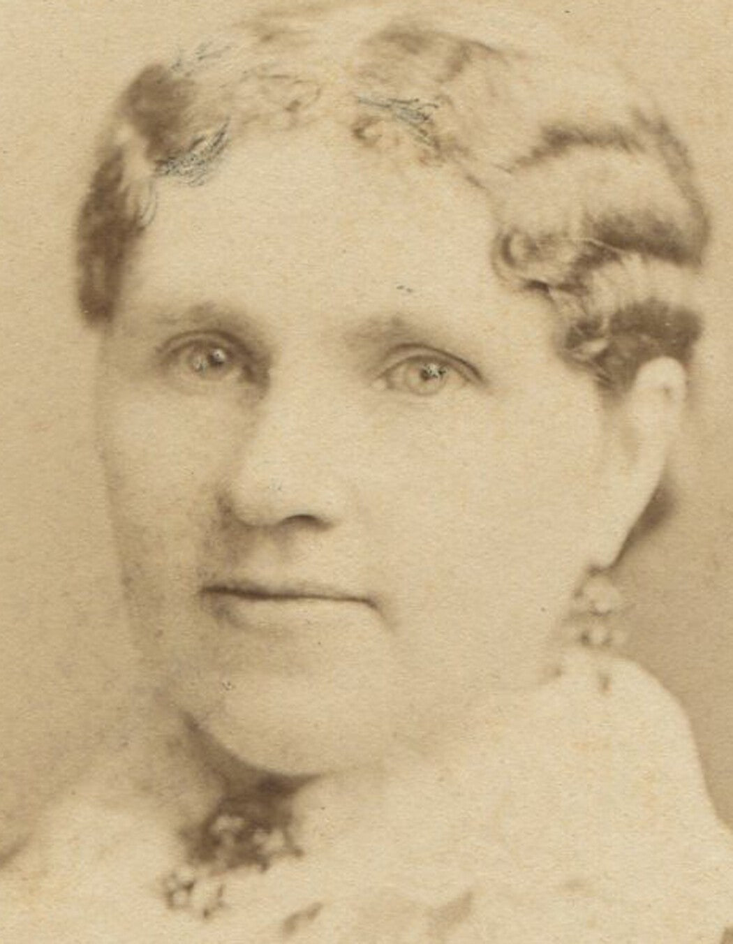 Vintage cabinet card portrait: woman with crimped curls and deep-set eyes,