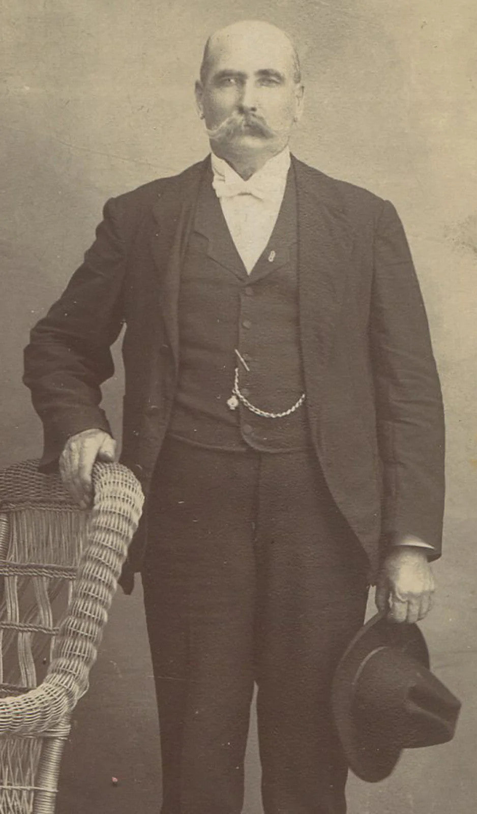 MAN W/BIG MUSTACHE, STIFFLY POSED HOLDING HAT. CABINET CARD.