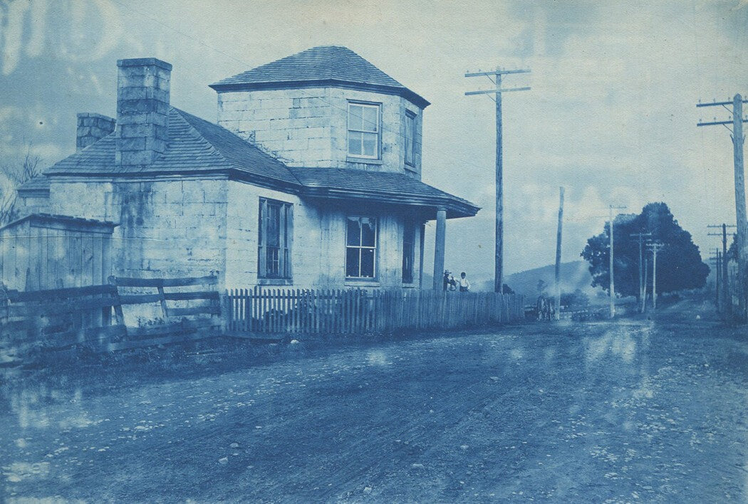 Vintage cyanotype photograph: uniquely shaped house by road, electric poles,