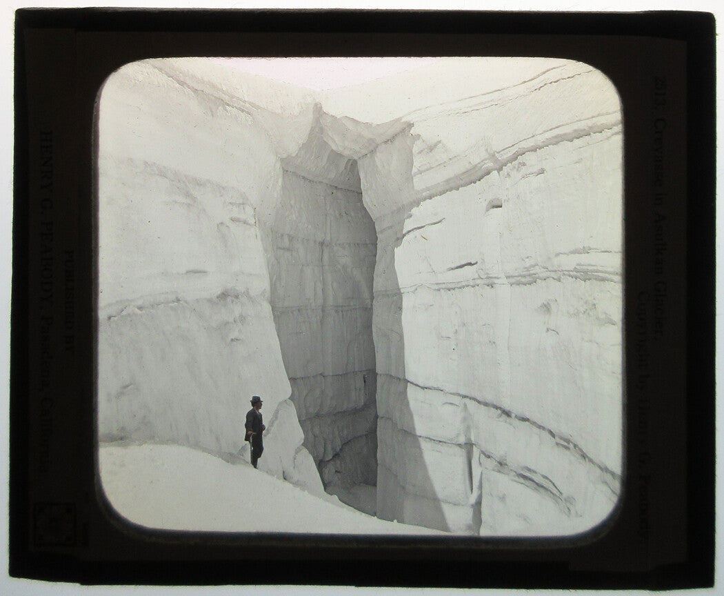 MAN STANDING AT ASULKAN GLACIER.PHOTO ON GLASS, HAND COLORED.