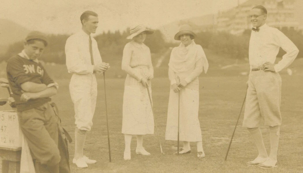 BORED CADDY W/ RICH COUPLES GOLFING. 1920s. TONED PRINT.