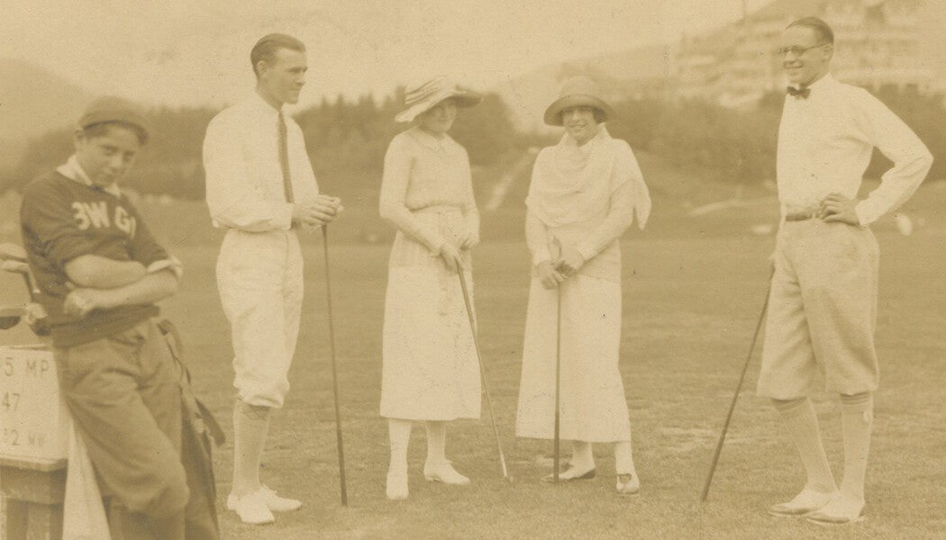 BORED CADDY W/ RICH COUPLES GOLFING. 1920s. TONED PRINT.
