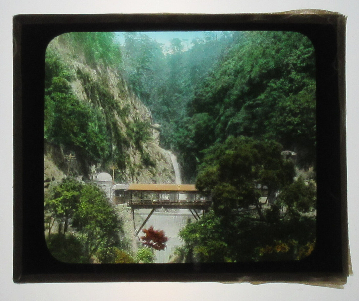 JAPANESE COVERED BRIDGE. BEAUTIFULLY HAND COLORED PHOTO ON GLASS.
