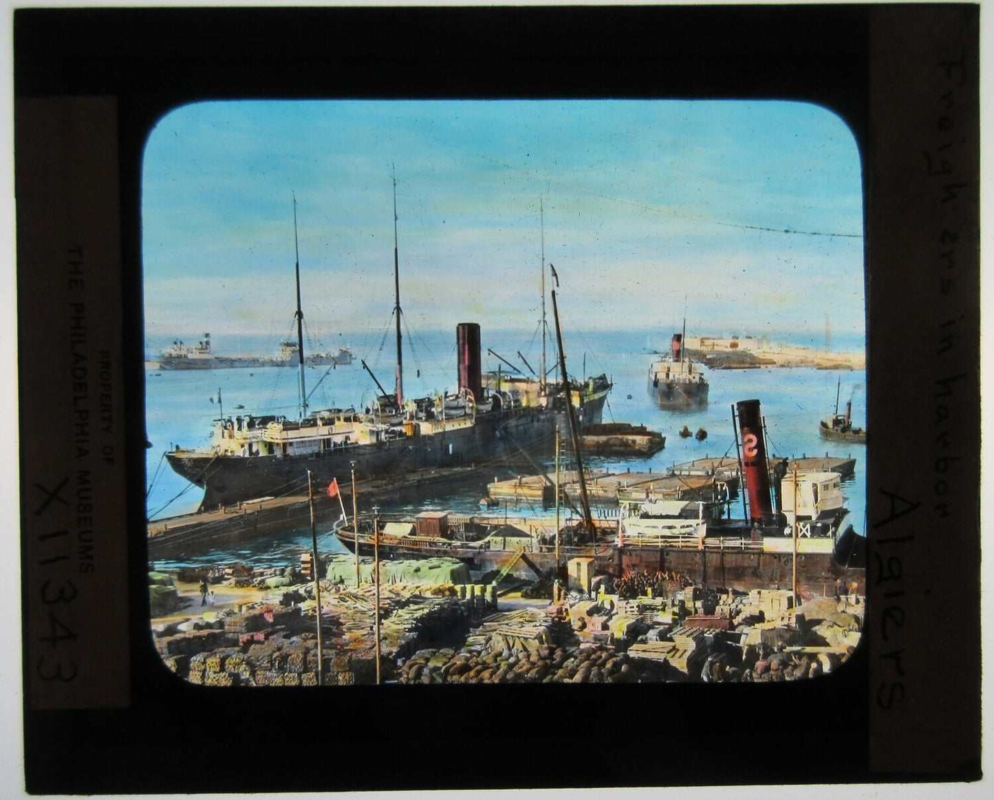 FREIGHTERS IN HARBOR, ALGIERS. HAND COLORED PHOTO ON GLASS.