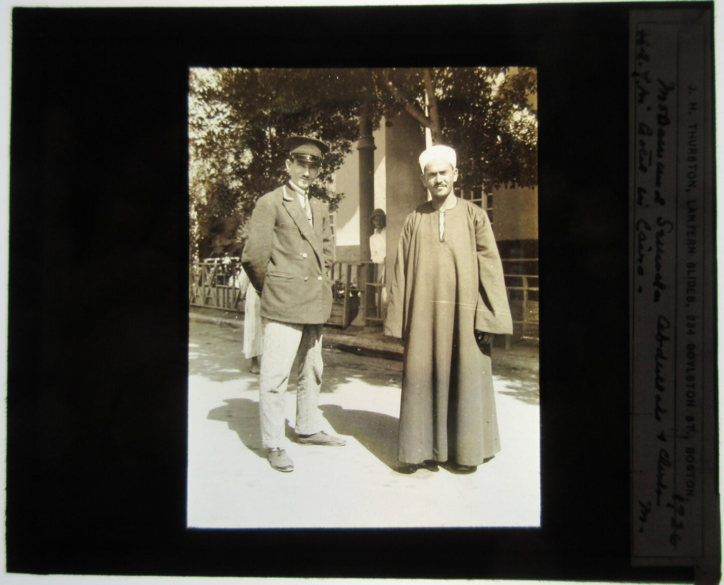 MAN IN UNIFORM POSED W/MAN IN ARAB CLOTHING. TINTED LANTERN SLIDE.