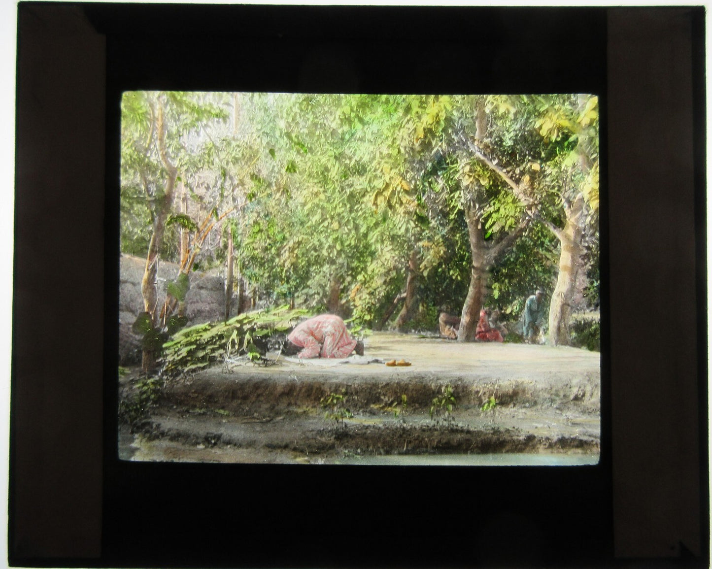 MAN PRAYING. HAND COLORED PHOTO ON GLASS.