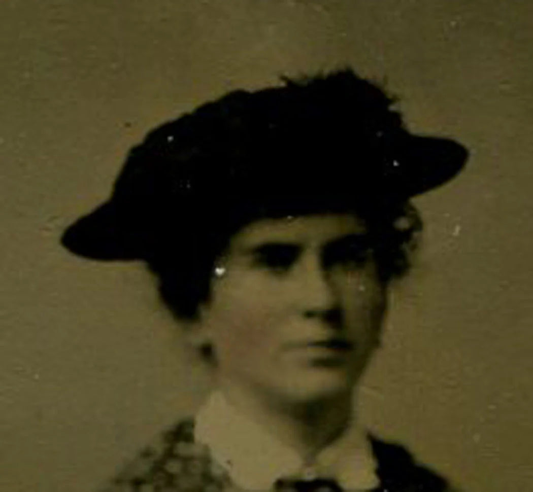 WOMAN WEARING HAT, SEATED IN FRONT OF PAINTED BACKGROUND. TINTED TINTYPE.