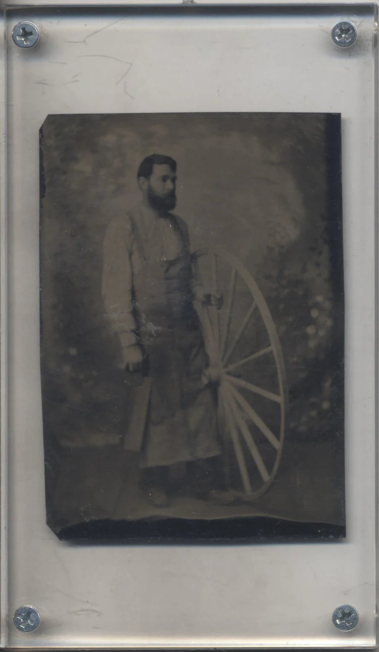 OCCUPATIONAL PORTAIT OF MAN IN APRON W/ SAW & LARGE WAGON WHEEL