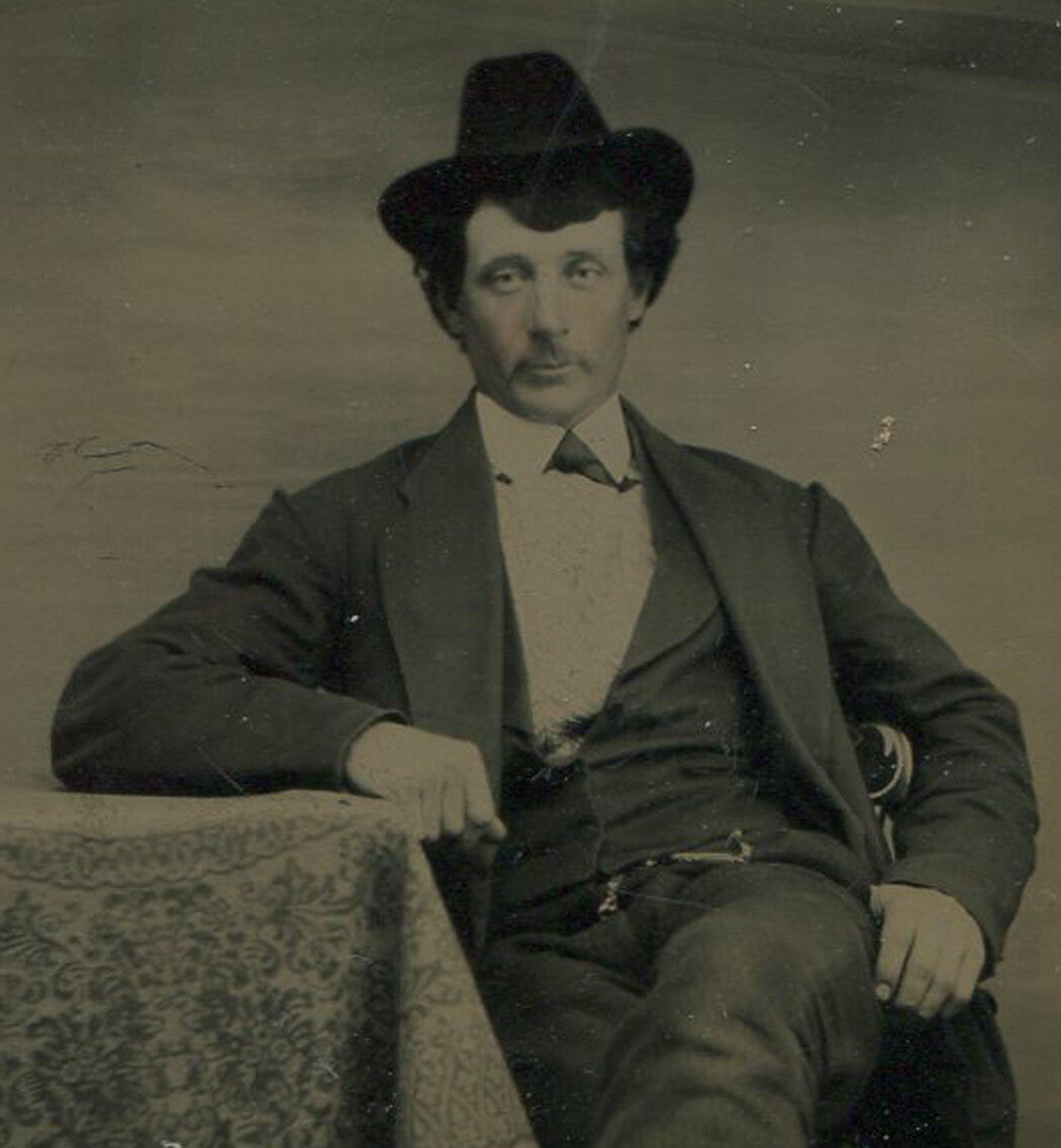 MAN WITH BUSHY HAIR AND SMALL COWBOY HAT. TINTED TINTYPE.