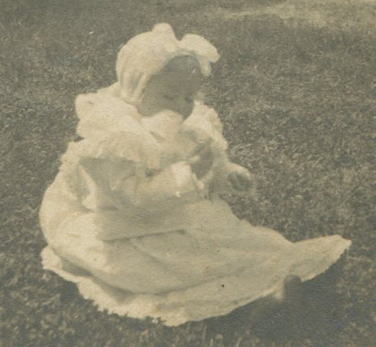 BABY SEATED ON LAWN. ROUND SILVER PRINT, MOUNTED ON CARD. 4.25 X 4.25 IN.