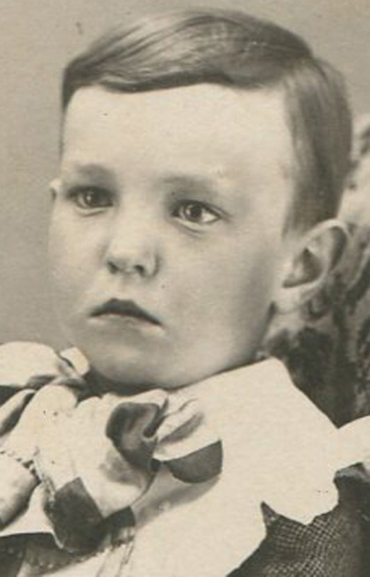 YOUNG BOY, FANCY OUTFIT, CROSSED LEGS, RELAXED POSE. SILVER PRINT, 1900.