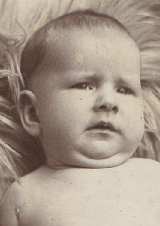 BABY WITH SLIGHT GRIMACE EXPRESSION. CABINET CARD.