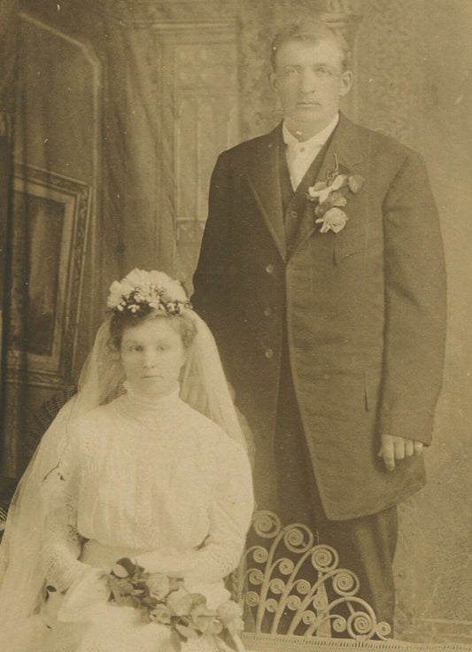 WEDDING PHOTO, COUPLE IN TRADITIONAL DRESS, FLOWERS. STUNNED EXPRESSIONS. B/W.