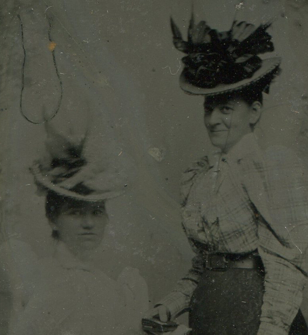 WOMEN IN LONG SKIRTS, BIG ORNATE HATS. TINTYPE IN PERIOD PAPER MAT.