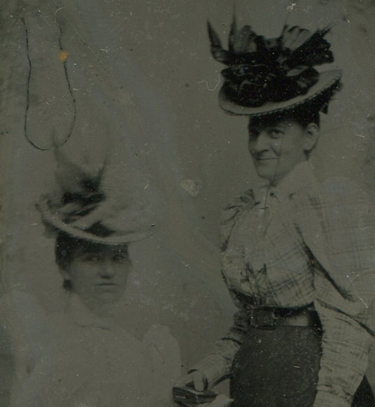 WOMEN IN LONG SKIRTS, BIG ORNATE HATS. TINTYPE IN PERIOD PAPER MAT.