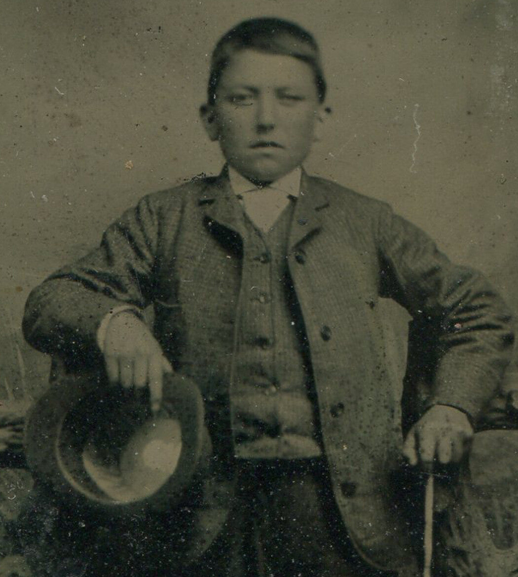 BOY POSED HOLDING HAT AND CANE, RUSTIC SETTING. TINTYPE.