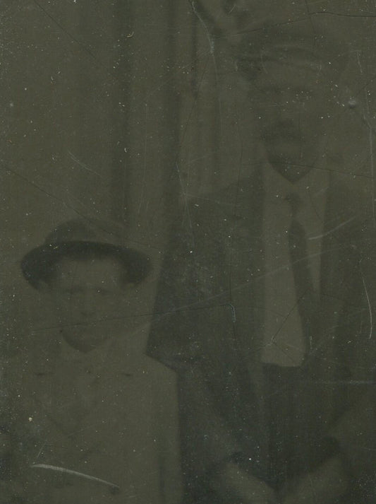 YOUNG BOY W/FATHER, BOTH IN HATS. TINTYPE IN PERIOD PAPER MAT.