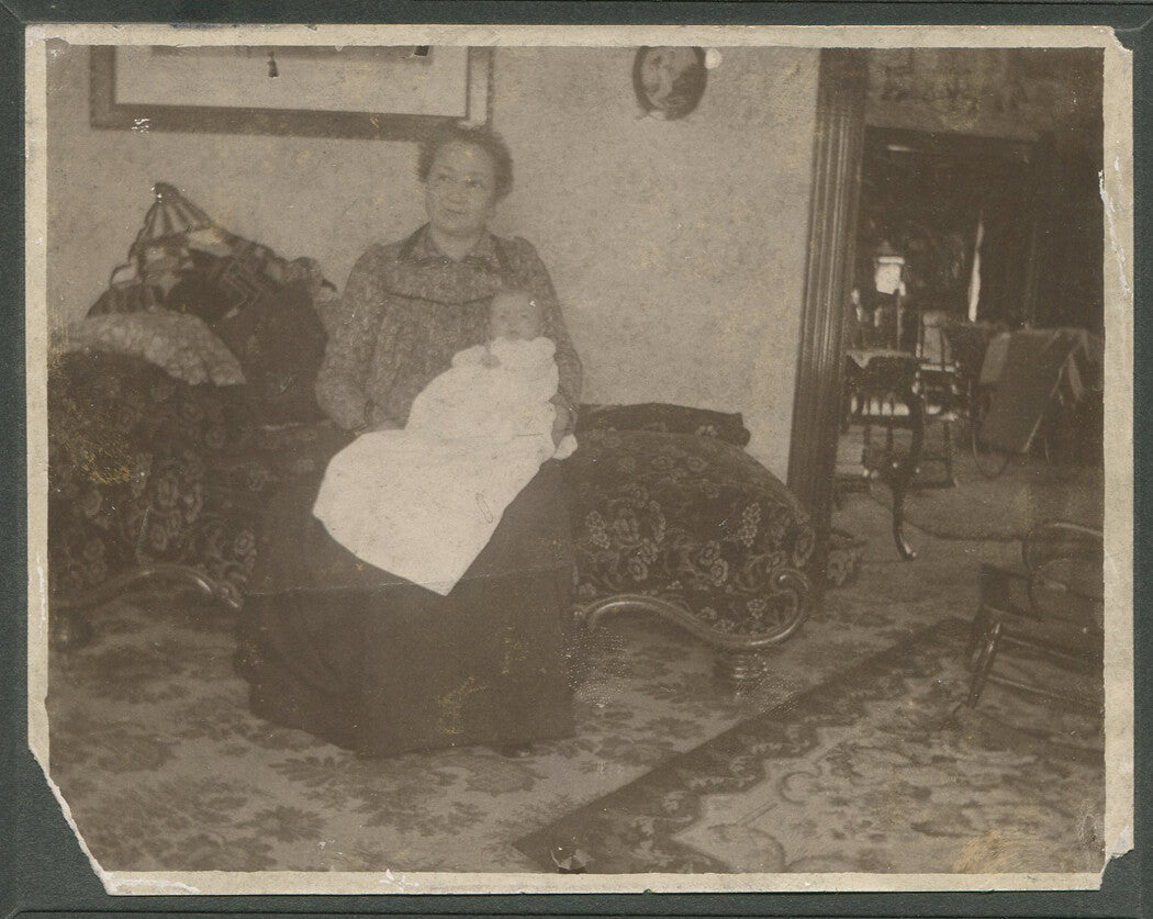 WOMAN HOLDING BABY. INTERIOR PHOTO. SILVER PRINT. CIRCA 1900.