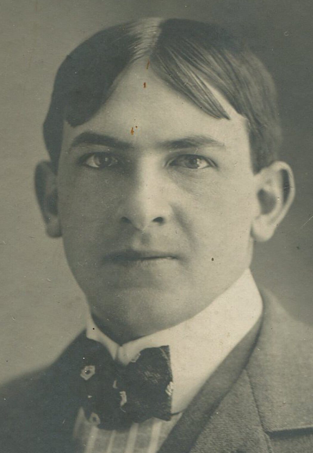 YOUNG MAN WITH UNFORTUNATE HAIR STYLE, COOL BOW TIE. CIRCA 1900.