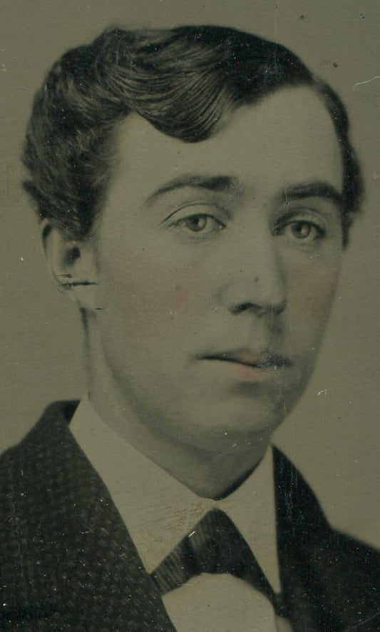 YOUNG MAN W/ WAVY HAIR OFF TO THE SIDE. TINTED TINTYPE IN PERIOD PAPER MAT.