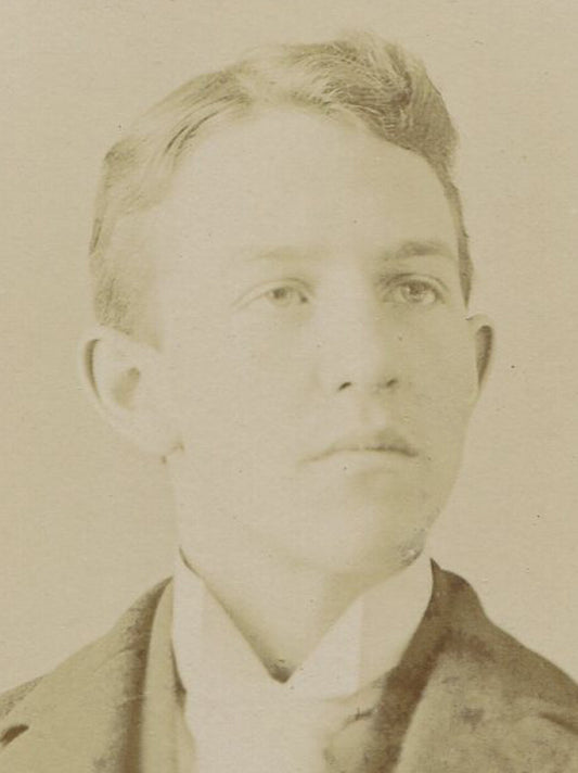 YOUNG MAN WITH ANGULAR FEATURES. SILVER PRINT ON EMBOSSED BOARD. CIRCA 1900.