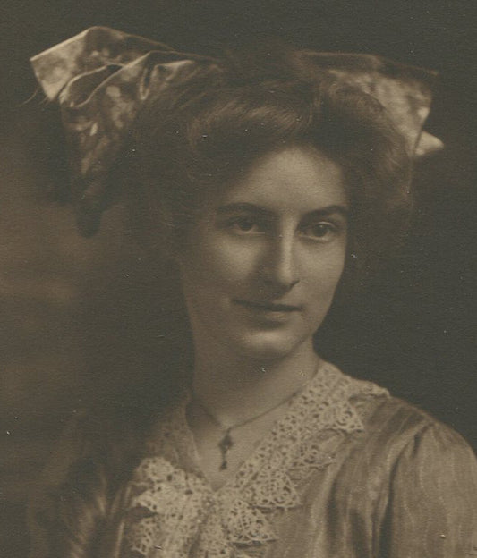 WOMAN WITH VERY LARGE BOW HEAD PIECE. TONED SILVER PRINT, 1900.