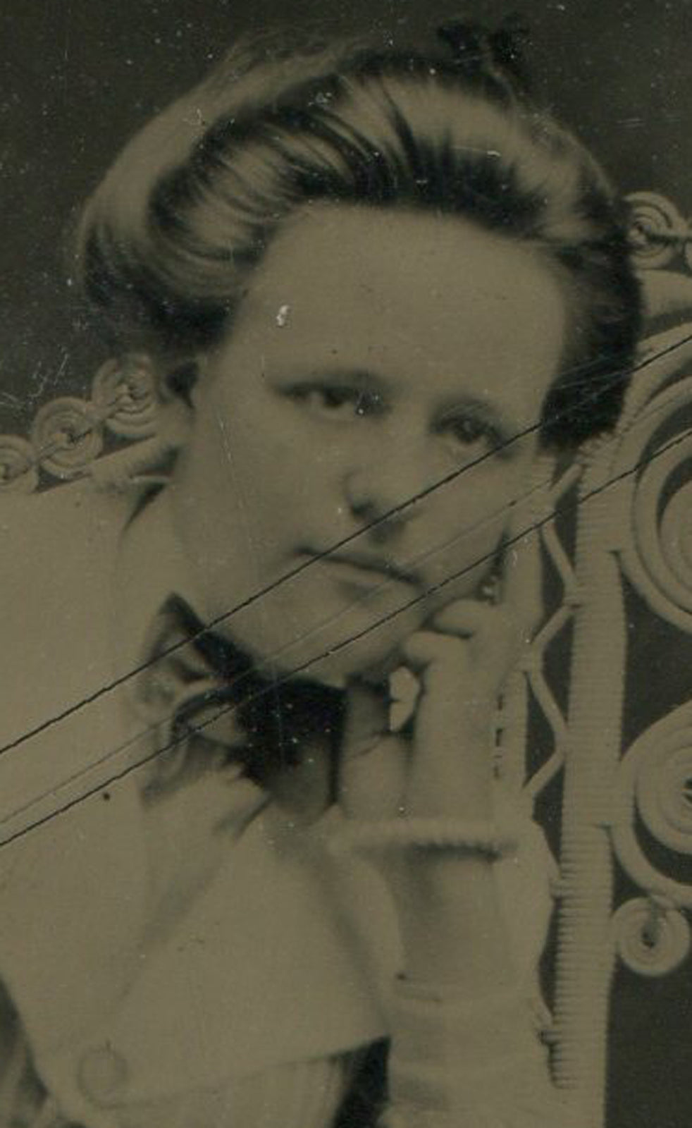 WOMAN POSED, CHIN IN HAND, ELBOW ON WICKER CHAIR. TINTYPE.