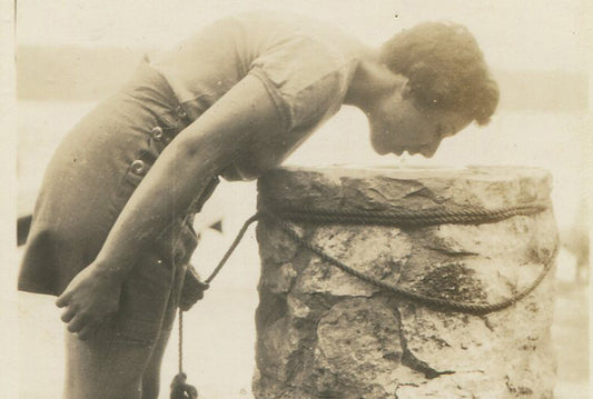 YOUNG WOMAN IN SHORT SKIRT BENT OVER AT DRINKING FOUNTAIN. 1940s.