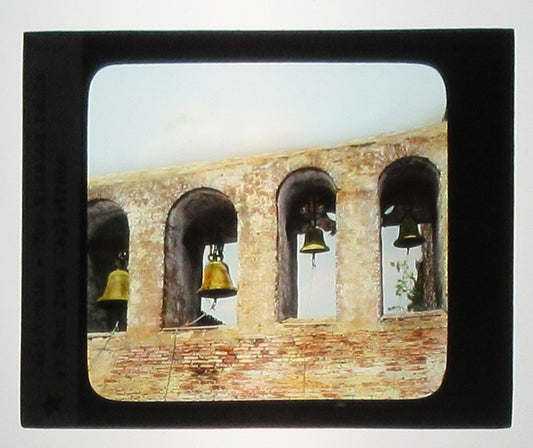 THE MISSION BELLS AT SAN JUAN CAPISTRANO. HAND COLORED PHOTO ON GLASS.