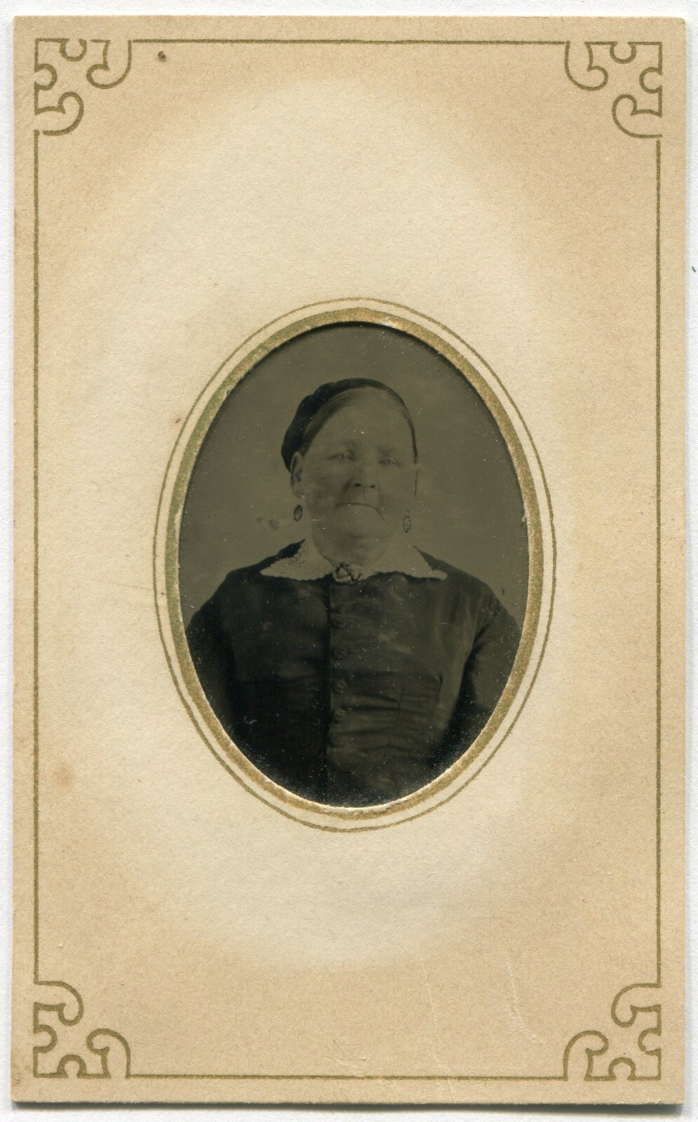 OLDER WOMAN, EARRINGS, KNOWING EXPRESSION. TINTYPE IN PERIOD PAPER MAT.
