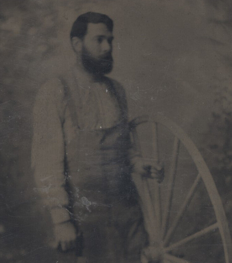 OCCUPATIONAL PORTAIT OF MAN IN APRON W/ SAW & LARGE WAGON WHEEL