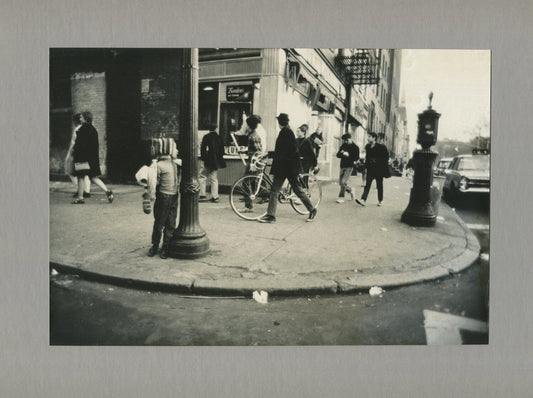 BUSY STREET SCENE, MAN W/BIKE, CHILD LOOKS ON. NYC, 1970s. B&W PHOTO.